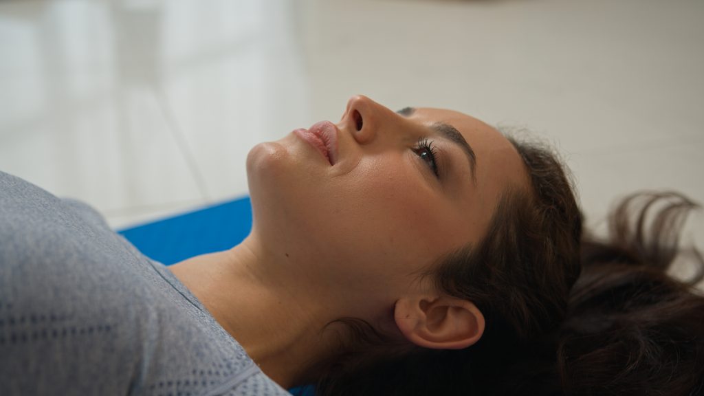 A person lies on their back on a blue mat, looking upward, finding solace and clarity as they reflect on understanding anxiety and its impact on mental health.