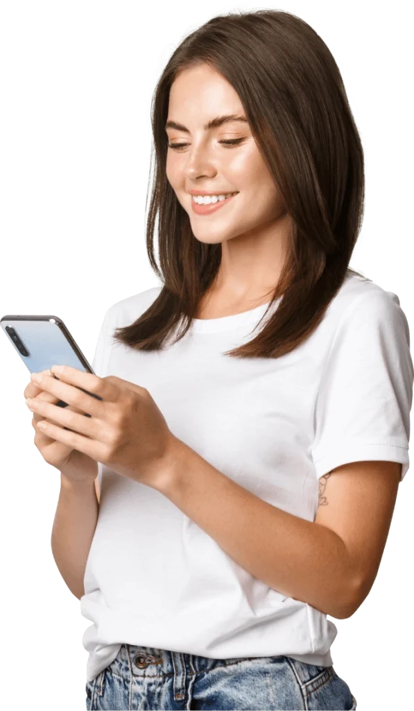Woman in a white T-shirt and jeans looking at a smartphone, smiling.